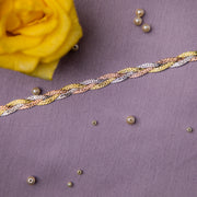 A close-up image of a sterling silver bracelet with a fishtail braid pattern, displayed on a textured background with a yellow flower and pearls scattered around.